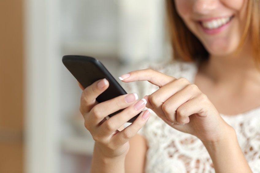 Close up of a woman hand texting on a smart phone at home with an unfocused background