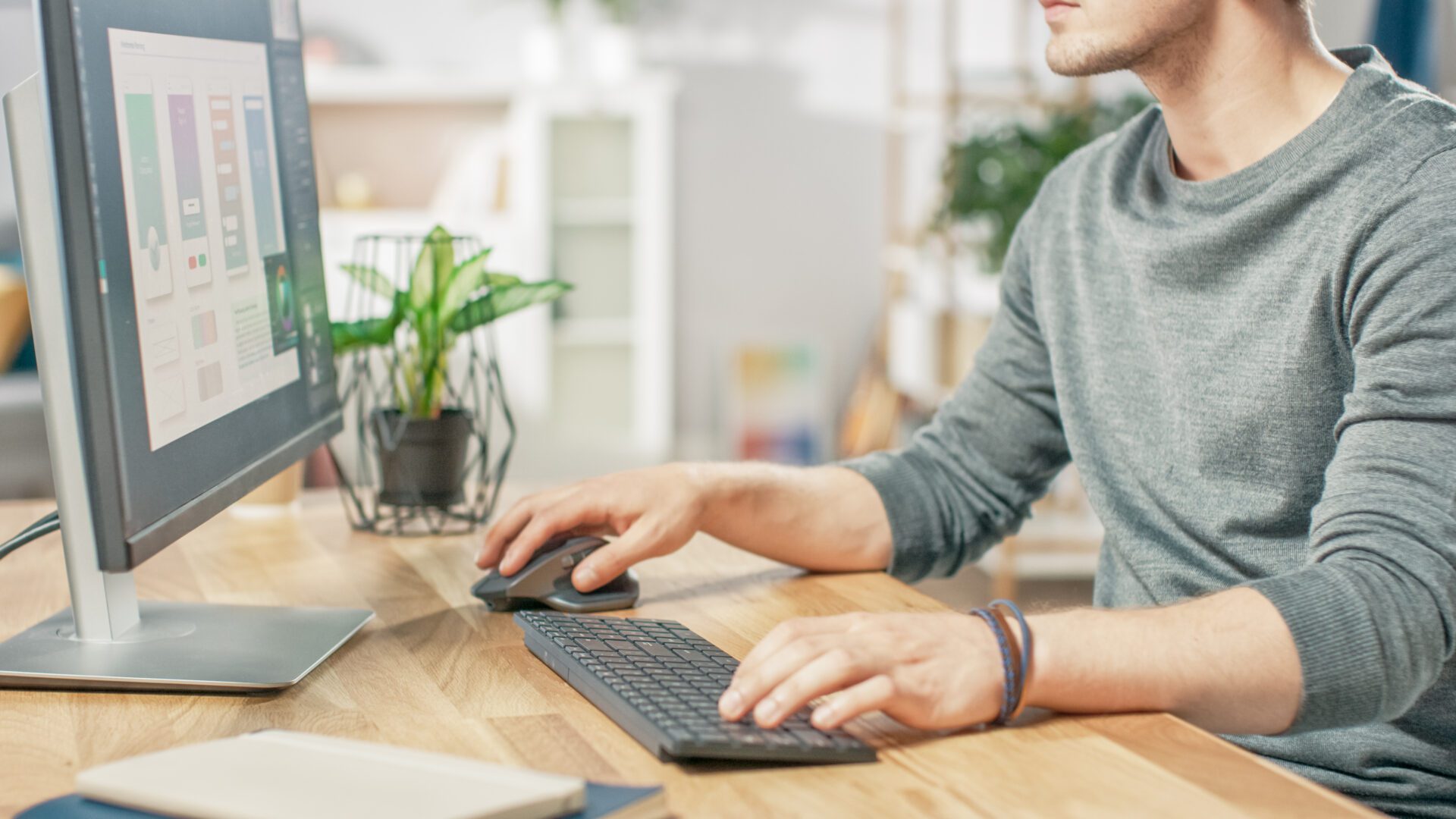 Close-up Shot of Man Using Computer and His Hands Typing on a Keyboard and Using Mouse. In the Background Cozy Living Room. Light Atmosphere.